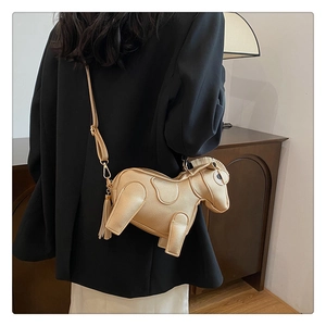 Detail of creative gold pony-shaped shoulder bag with metal chain strap and tassels