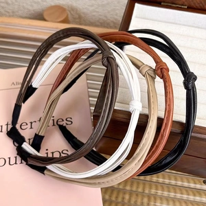 Detail of four thin leather knotted headbands in black, brown, and white colors