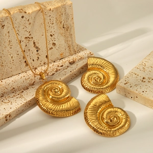 Detail of 18K gold plated stainless steel seashell necklace and earrings on beige stones