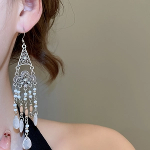 Detail of ethnic tassel earrings featuring silver hollow geometry and crystal drops
