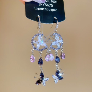 Macro detail of S925 silver floral earrings with crystals and hanging tassels