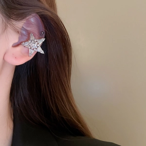 Close-up of sparkling star-shaped silver ear cuff with inlaid crystals on a model's ear