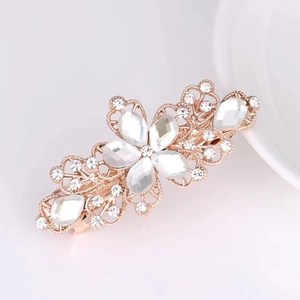 Detailed view of a small golden flower hair claw clip with sparkling clear crystals