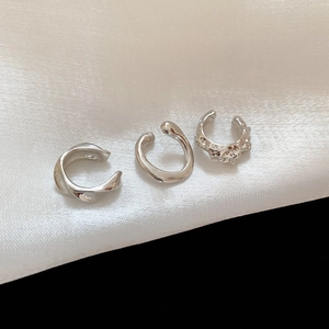 Detailed macro view of S925 sterling silver ear cuffs set on white silk fabric