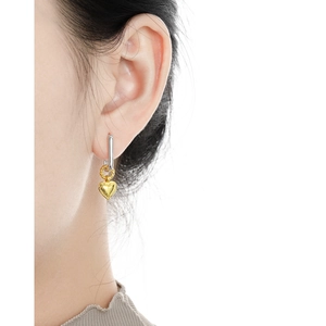 Elegant two-tone S925 silver heart dangle earrings worn by a model on a white background