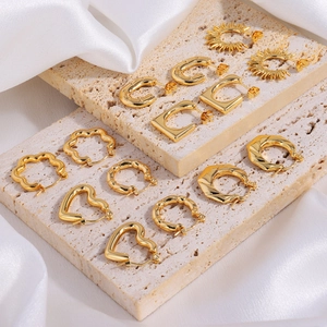 Multiple gold flower and geometric earrings on stone pedestals with silk background