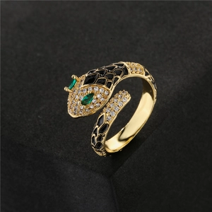 Gold snake ring with black enamel, green gemstone eyes, and sparkling zircon accents