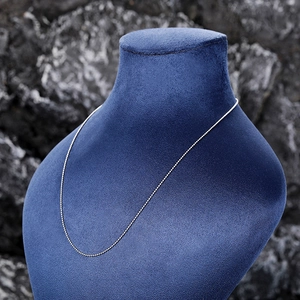 Detail of a silver beaded chain necklace displayed on a blue velvet neck mannequin