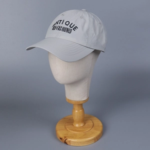 Detail of light gray baseball cap featuring black Antique Old-Fashioned embroidery text