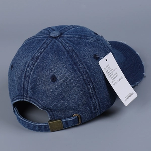 Detail of distressed denim baseball cap with frayed brim and adjustable metal buckle
