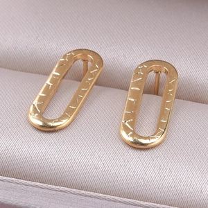 Detailed macro view of gold oval earrings with irregular texture on champagne satin