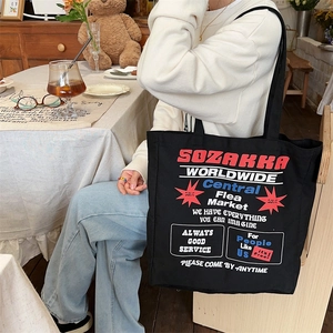 Lifestyle shot of large capacity black canvas tote bag with retro print in a cafe setting