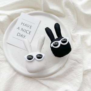 Detail of plush bunny phone grips in black and white with sunglasses on a white plate