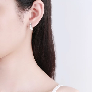 S925 sterling silver hoop earrings with white pearls worn by a model on a purple background