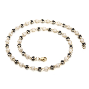 Elegant gold chain necklace with alternating black and white heart charms on white background