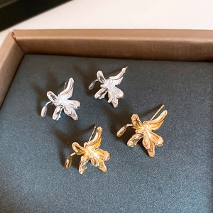 Detailed close-up of lily flower earrings in gold and silver finish on display pad