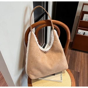 Detail of camel faux suede tote bag with beige shearling trim on a wooden chair