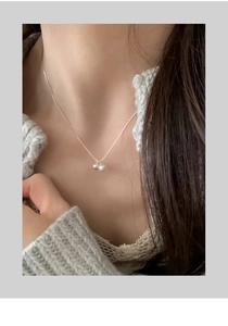 Close-up of dual silver bead pendant necklace on model with polished metallic finish