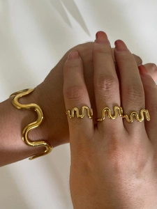 Polished gold wave jewelry set featuring a wide bracelet and matching rings for women