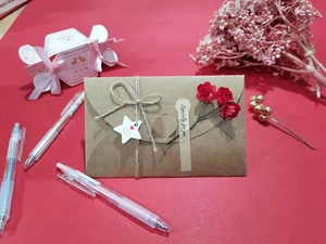 Flat lay of brown kraft paper envelopes with twine, heart tags, and a white gift box
