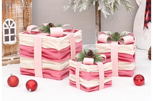 Detailed view of pink velvet Christmas gift boxes with pine cones and silk ribbon bows