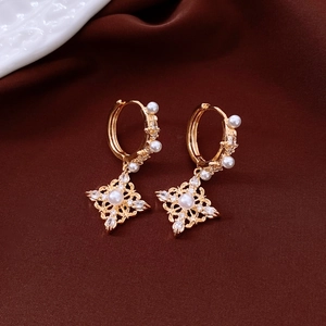 Détail de boucles d'oreilles plaquées or 18 carats avec pendentifs losanges et perles