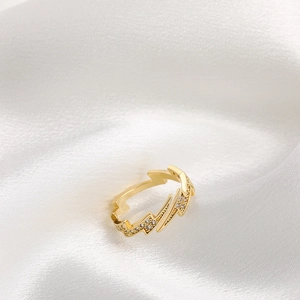 Polished 18K gold lightning bolt open ring with pavé zircon diamonds on white silk