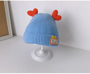 Close-up of blue knit baby hat with red heart accents and Good Life woven patch