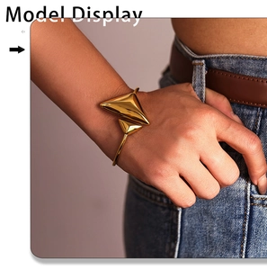 Detailed view of polished 18K gold-plated triangular open bangle worn on model's wrist