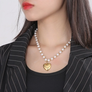 Vue détaillée du bracelet de perles avec un pendentif cœur doré brillant porté au poignet