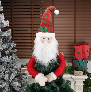 Detailed view of plush Santa tree topper ornament with red hat and green accents