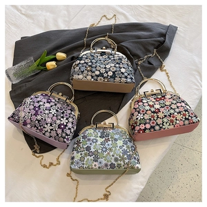 Detail view of shell bags with floral patterns, metal ring handles and gold chain straps