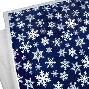 Close-up of snowflake printed flannel and thick white sherpa lining on a navy blue blanket