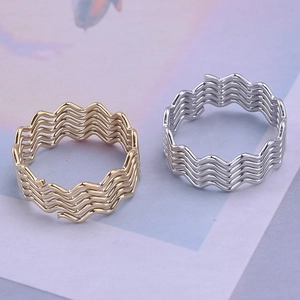 Detail view of wave-patterned 18K gold and silver rings with multilayered metal lines