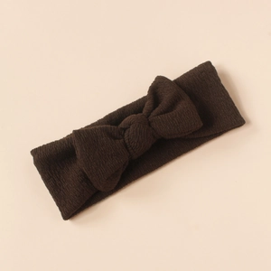 Close-up of a soft knitted dark brown baby headband with a fine texture bow design