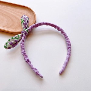 Detail of purple fabric headband with floral bow accent and soft cotton texture