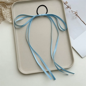 Detail of light blue silk bow hair tie with long tassels on a decorative tray