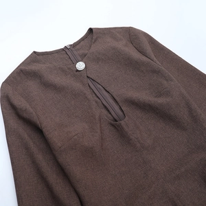 Detail view of round neckline with single white button and zipper on brown knit dress