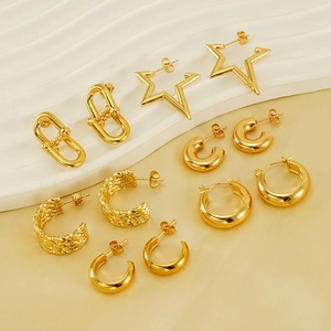 Detail of diverse gold stainless steel earrings set displayed on white textured props