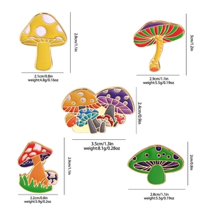 Set of five colorful cartoon mushroom enamel pins with gold trim on white background