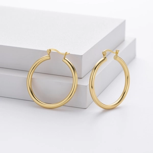 Detail view of high-polished gold-plated S925 silver hoop earrings on a white stand