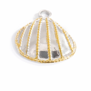 Macro shot of two-tone shell-shaped pendant in gold and silver finish on white background