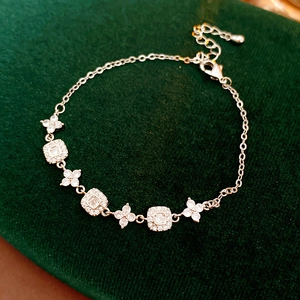 Detail of gold-plated square floral adjustable bracelet with cubic zirconia on green velvet