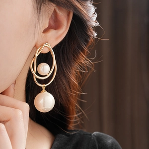 Close-up of irregular geometric gold pearl earrings worn by a model for a luxury look