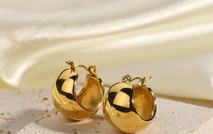 Detail of 18K gold plated chunky hoop earrings on silk background with stone texture