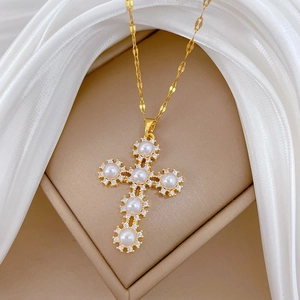 Detailed macro view of a gold cross pendant necklace with pearls and sparkling crystals