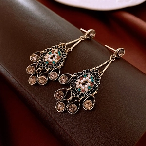 Close-up of vintage gold teardrop earrings with colorful rhinestones and pearls