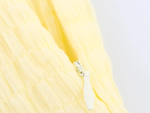 Macro shot of invisible zipper and soft textured fabric detail on a yellow dress
