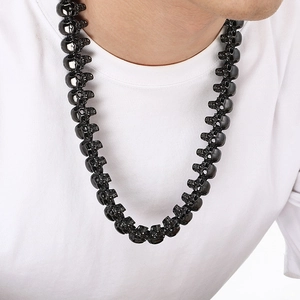 Detail of a black skull necklace for men showing polished gothic links on a model's neck