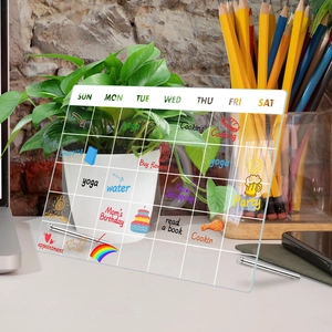Macro shot of clear acrylic weekly planner on a desk with metal stand and color handwriting